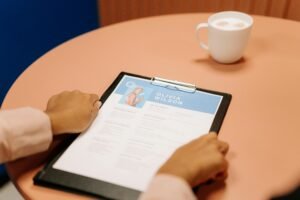 Close-up of hands holding resume during interview with coffee on table, highlighting workplace setting.